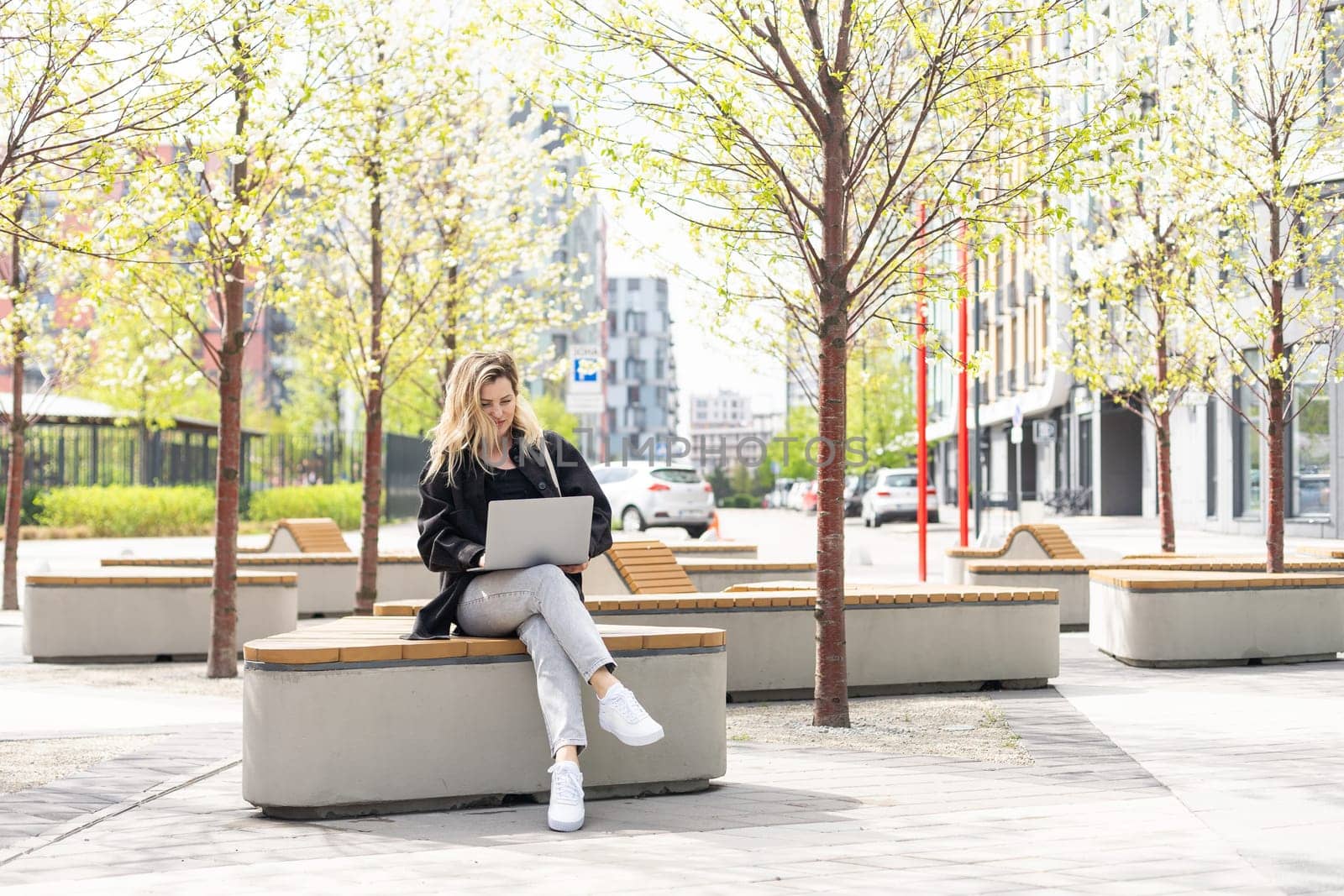 girl with a laptop on a bench in the park on a background of greenery by Andelov13