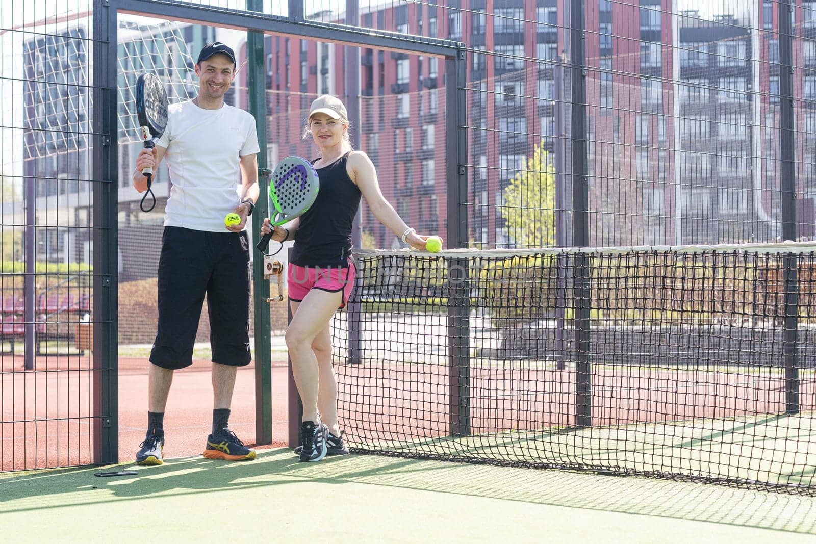 Ukraine Kyiv, April 02 2024. Young woman and man talking to each other after playing padel, walking along the net together. High quality photo