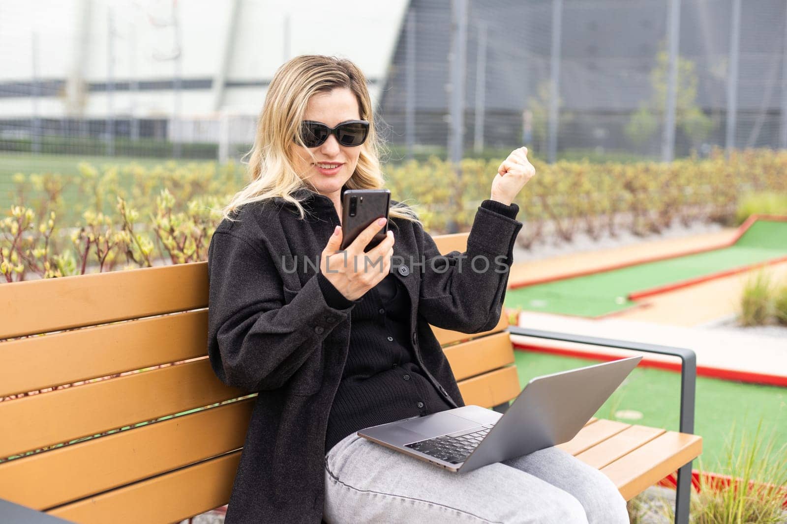 A businesswoman using a laptop on a golf course by Andelov13