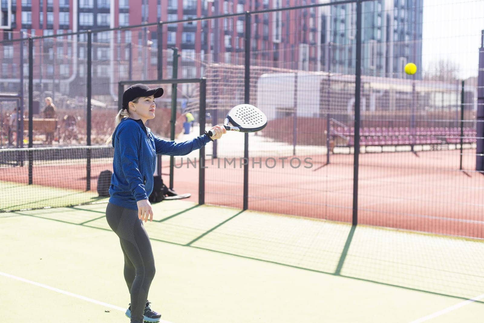 One woman with racquet and ball behind the net in paddle tennis court ready for training. High quality photo