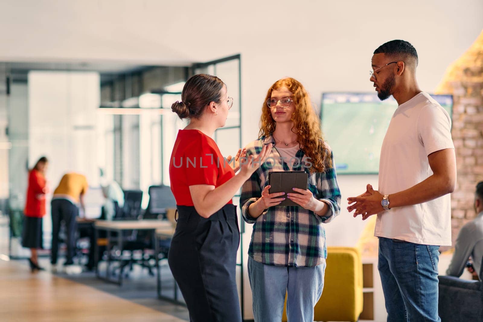 A group of young business individuals, including a girl with orange hair and an African American man, stands in a modern corporate hallway, collectively examining business progress on a smartphone, exemplifying dynamic collaboration and digital engagement. by dotshock