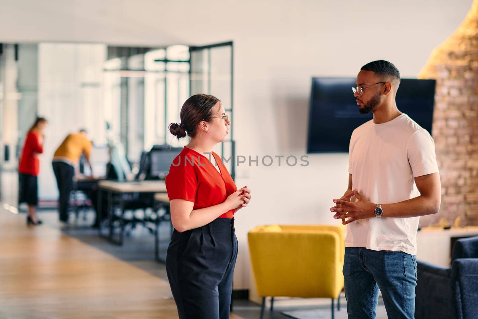 Young business colleagues, including an African American businessman, engage in a conversation about business issues in the hallway of a modern startup coworking center