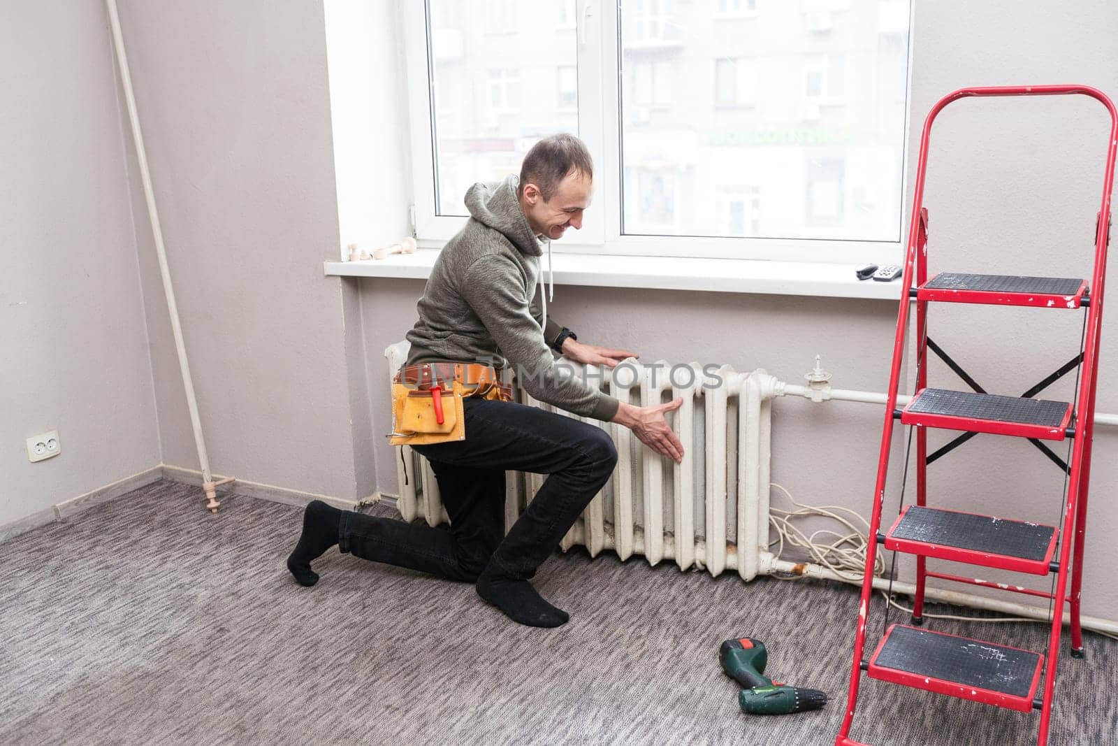 Worker replaces domestic radiator in the living room. High quality photo