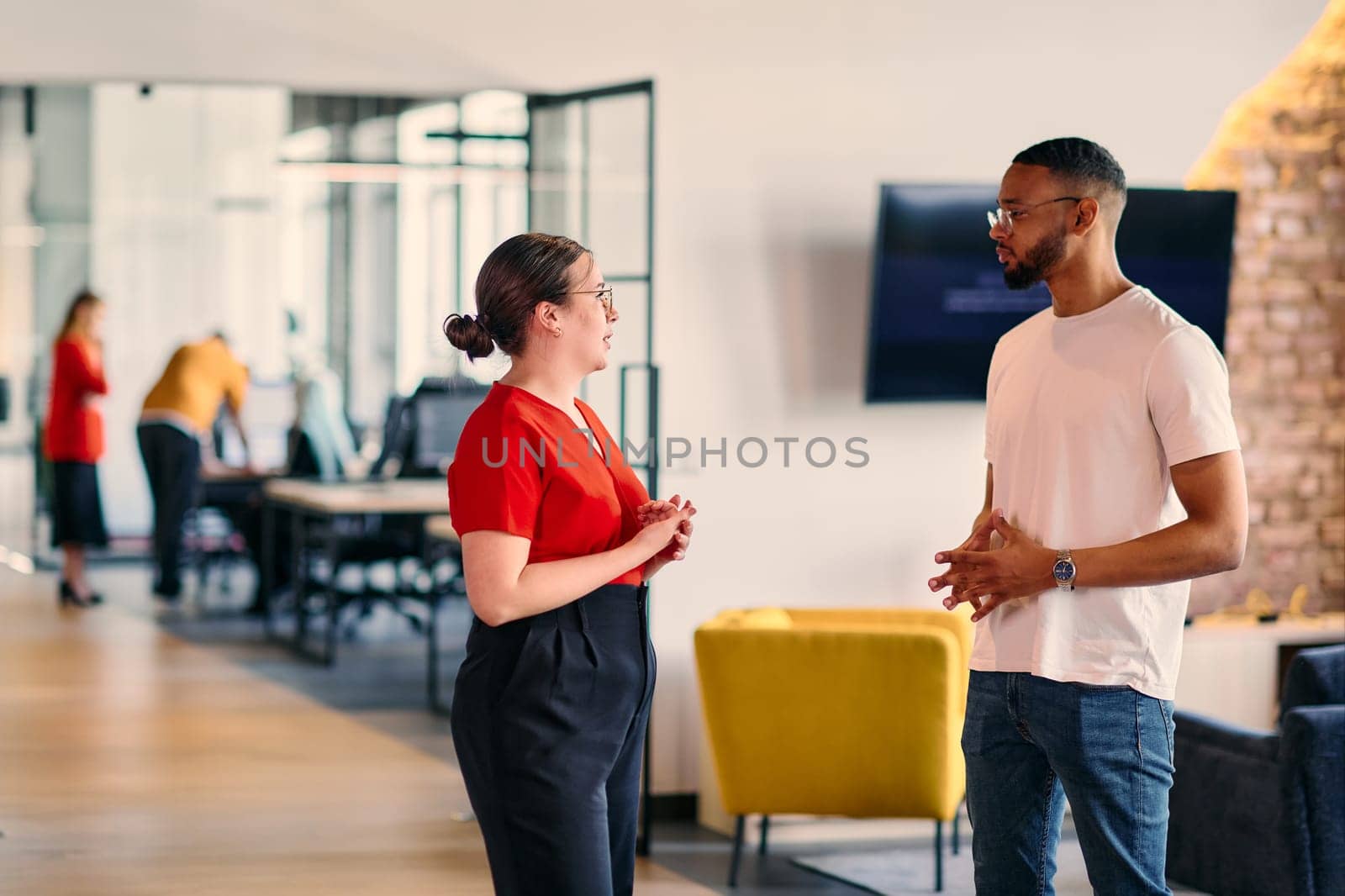 Young business colleagues, including an African American businessman, engage in a conversation about business issues in the hallway of a modern startup coworking center