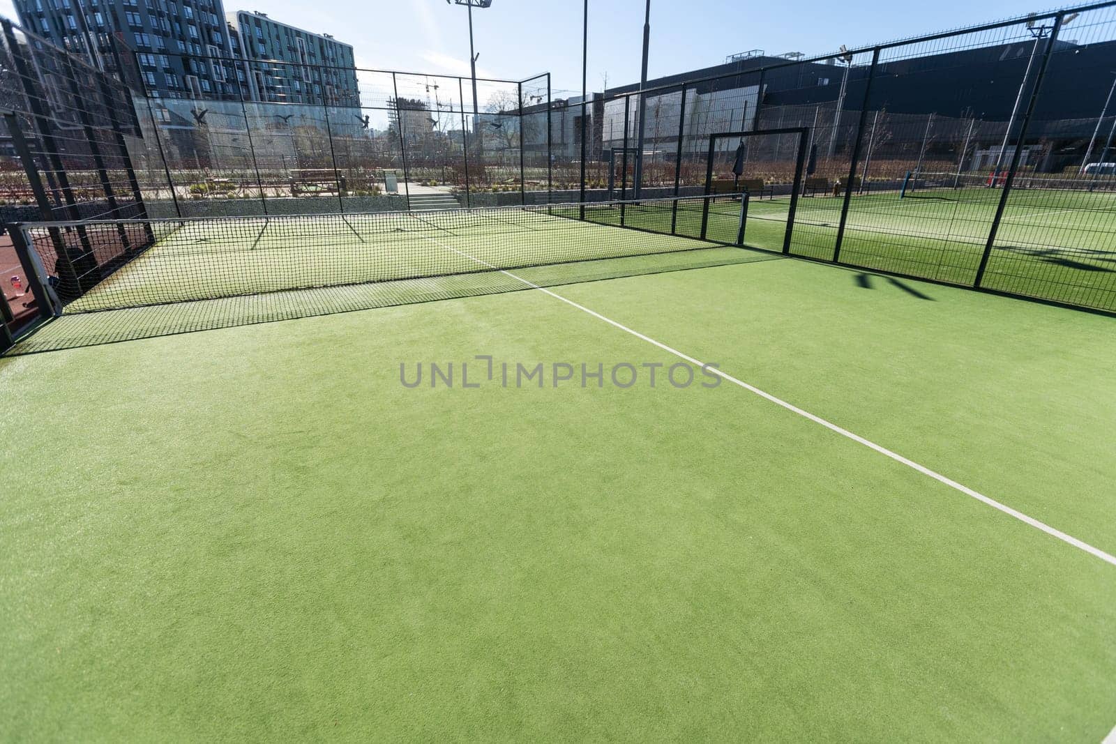 Landscaped areas of a residential development with a tennis court with high Plexiglas and metal fences. High quality photo