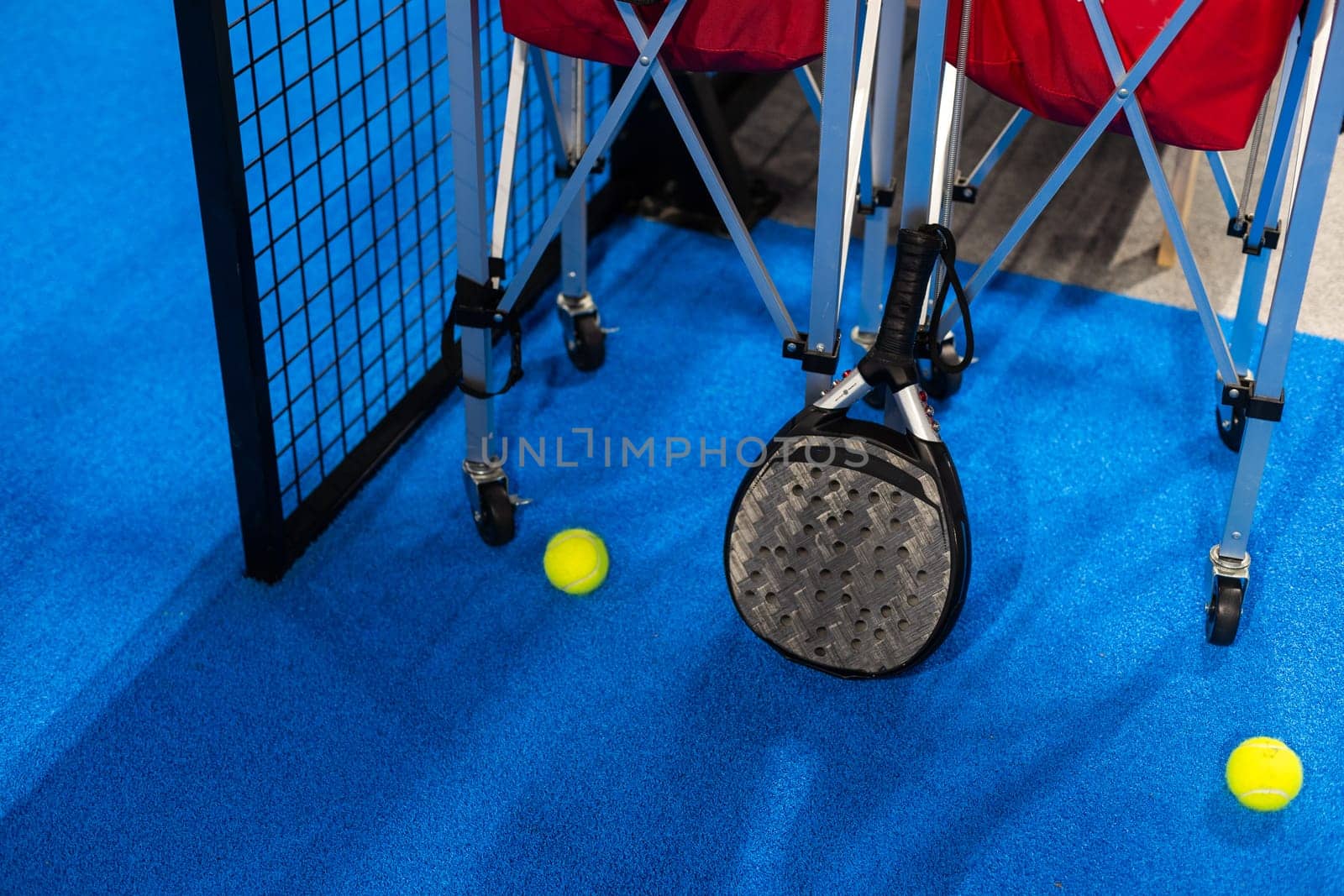 balls near the net of a blue padel tennis court. High quality photo
