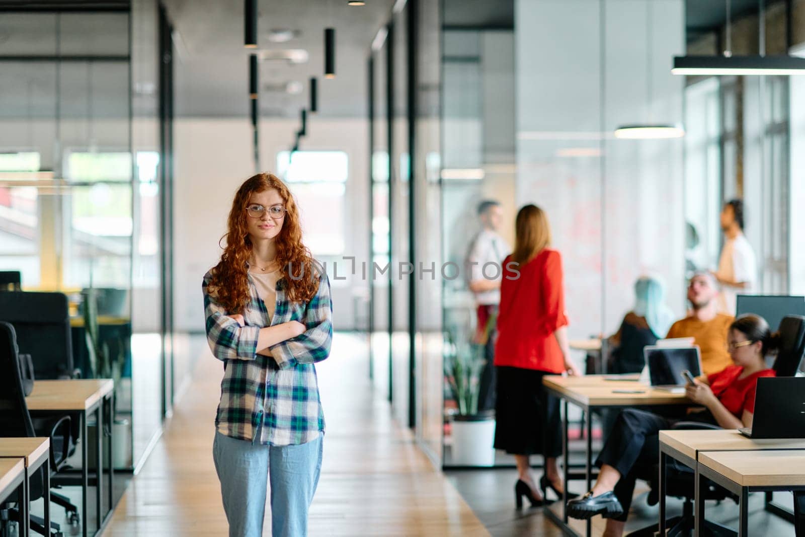 A portrait of a young businesswoman with modern orange hair captures her poised presence in a hallway of a contemporary startup coworking center, embodying individuality and professional confidence. by dotshock