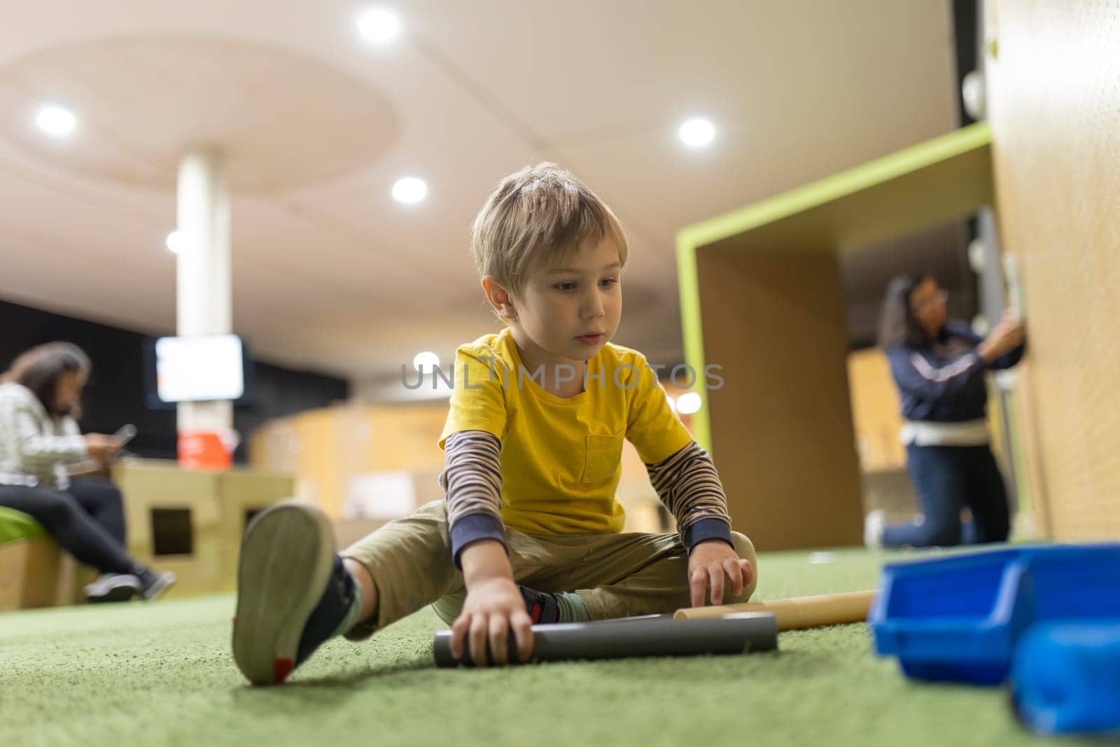 A young boy is sitting on the floor playing with a toy by Studia72