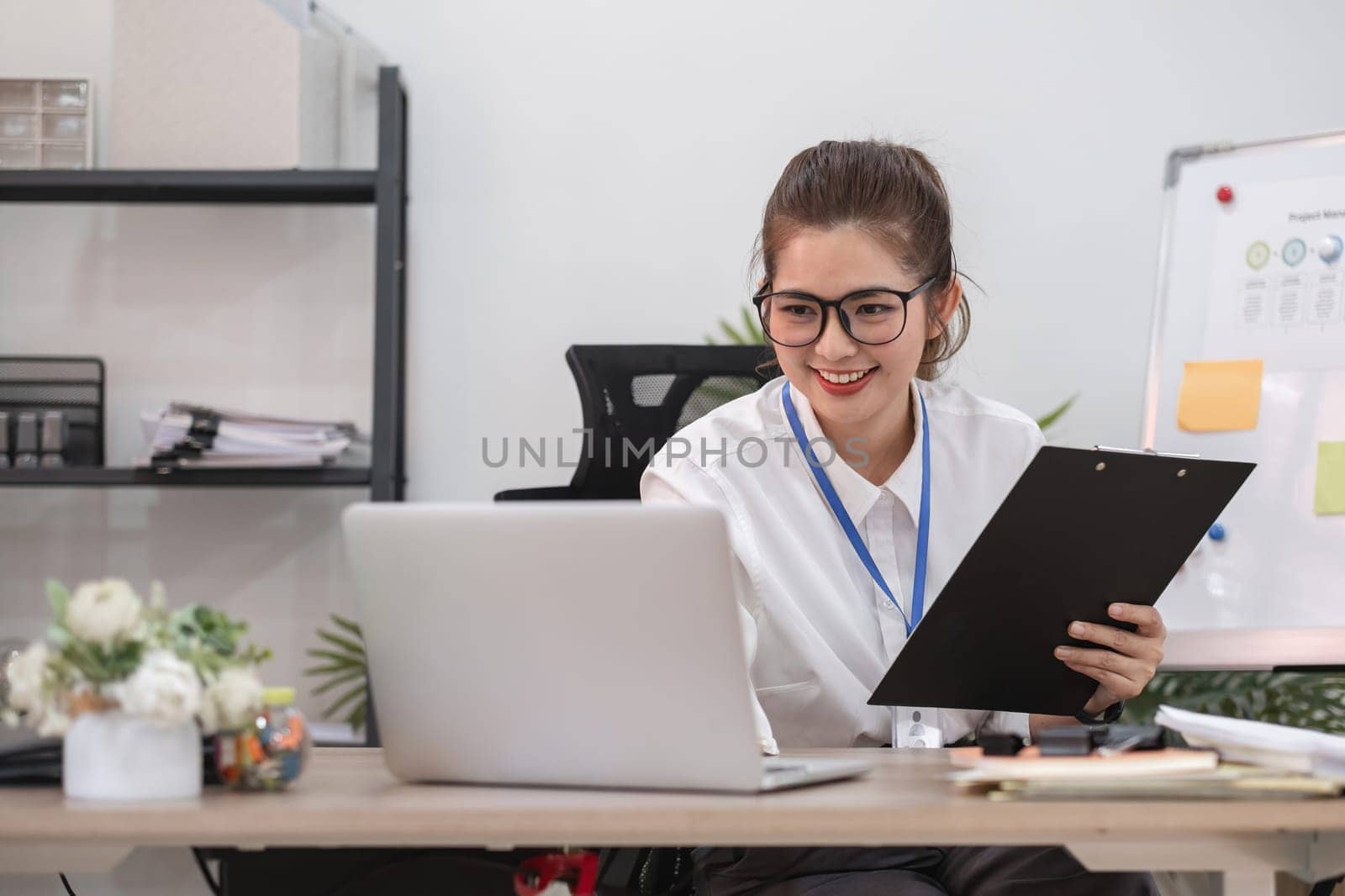 Young business woman meeting on laptop, doing paperwork in white office room by wichayada