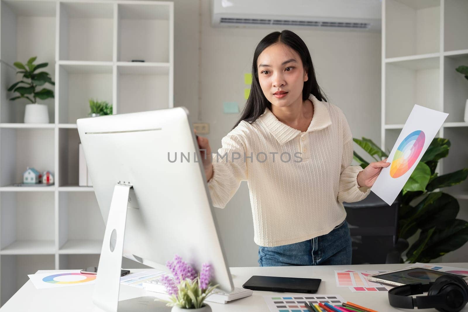 Female designer working in graphic design on computer Sit and choose colors and work intently in your office. by wichayada