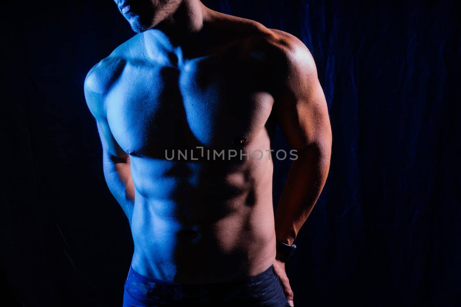 Confident, attractive shirtless muscular young man topless in studio by Zelenin