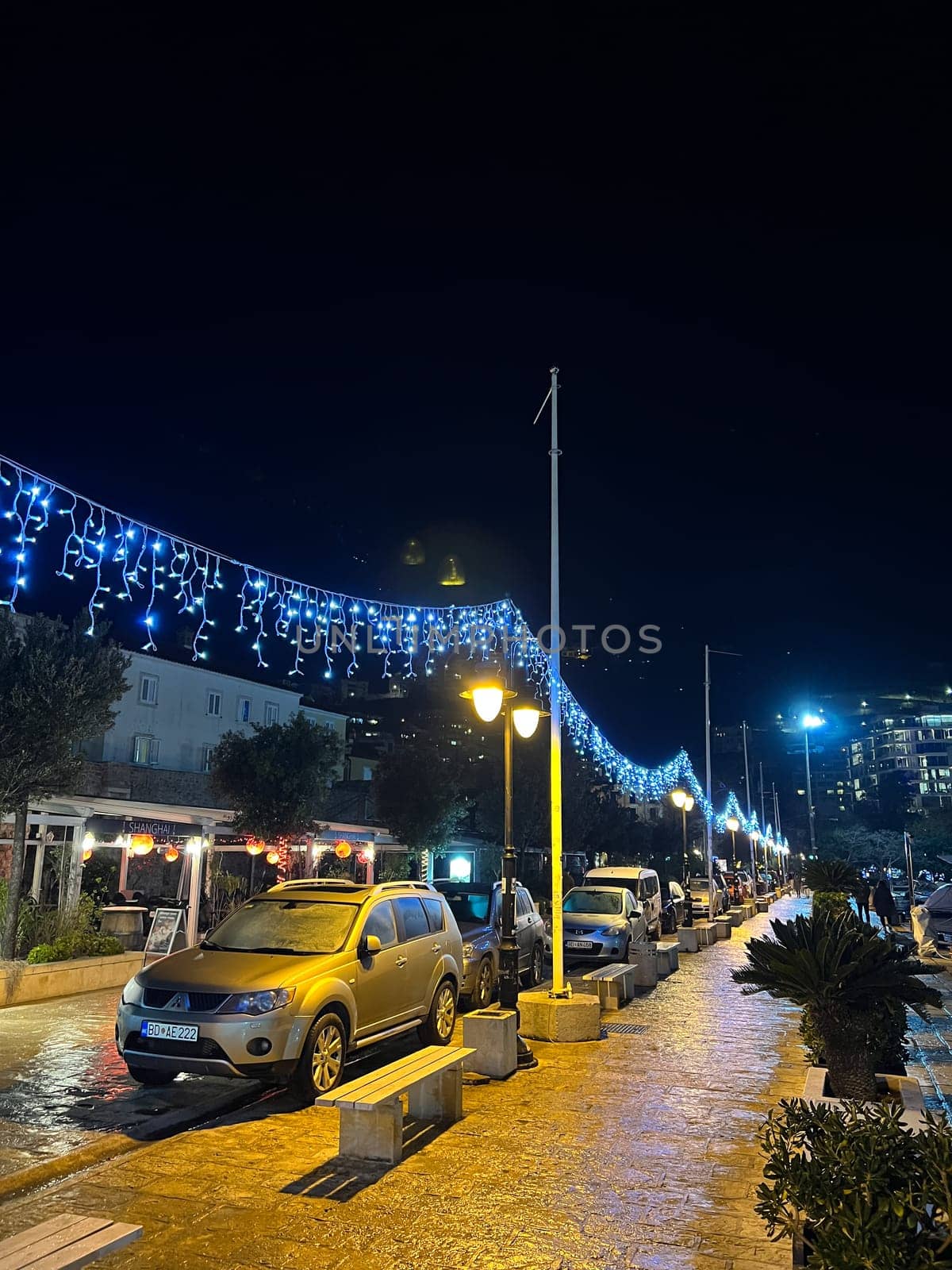 Parked cars stand along the paved road in night illumination. High quality photo