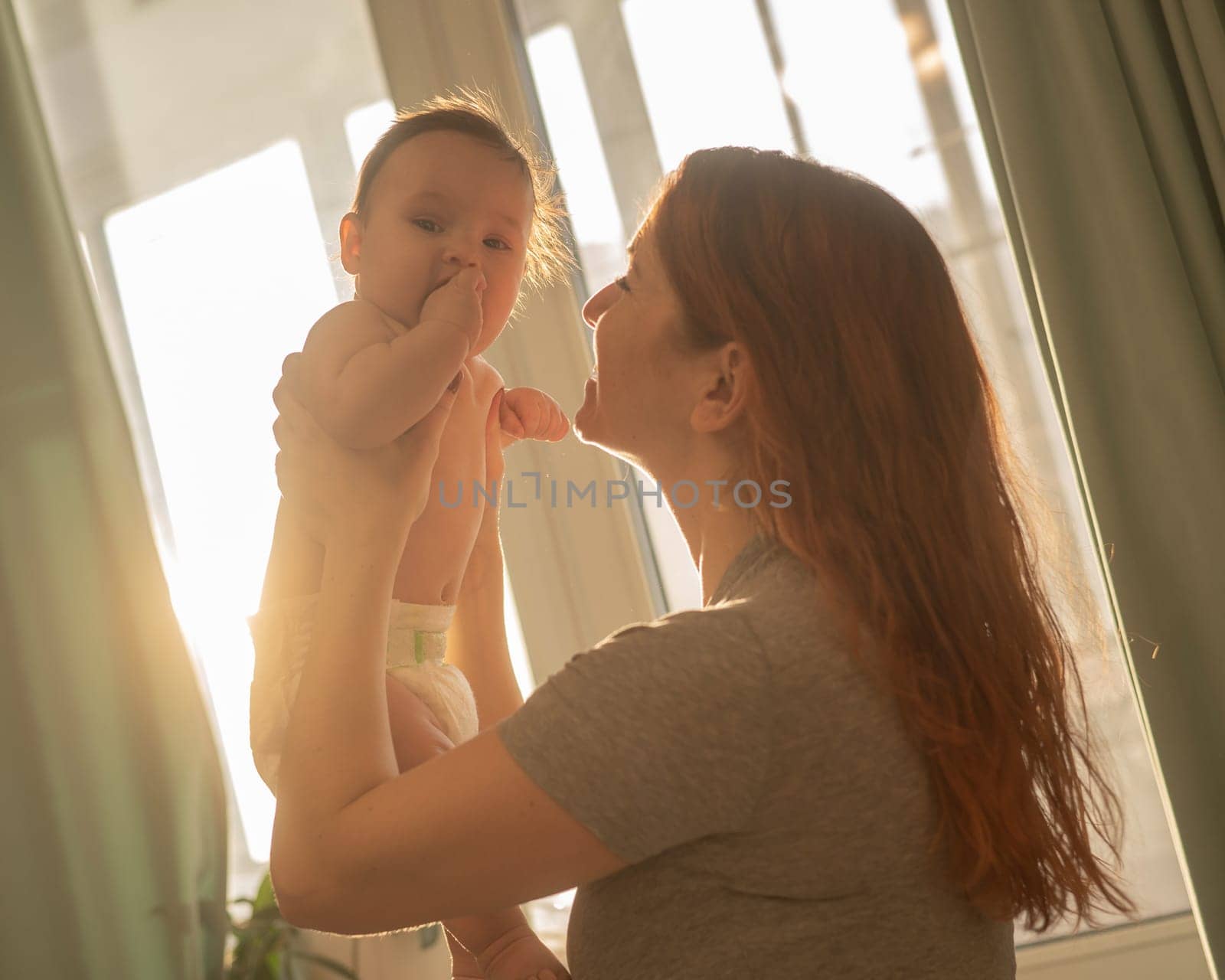 Caucasian woman gently lifts up her newborn son. by mrwed54