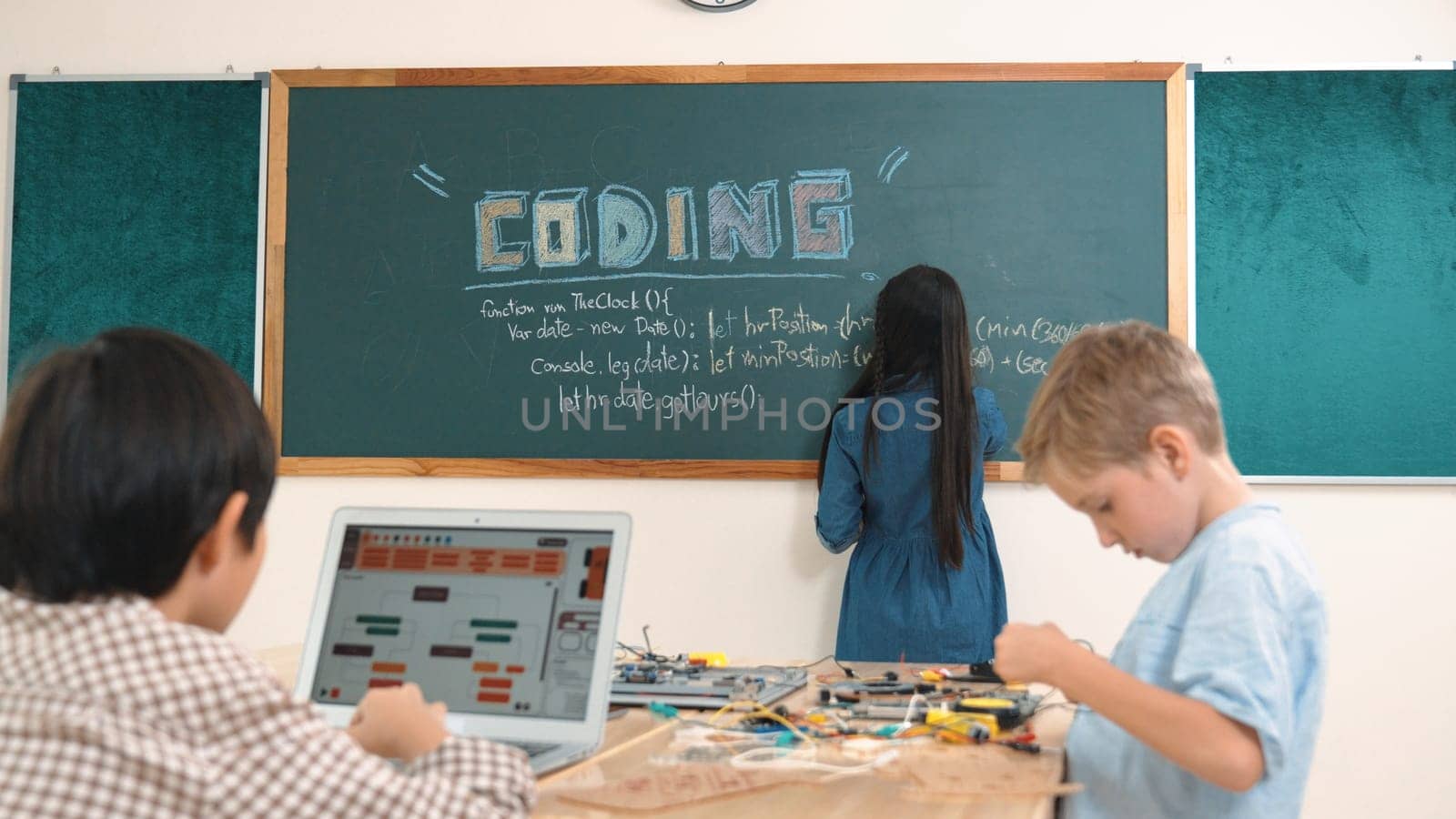 Asian boy coding program while caucasian friend fixing electric board at STEM class. Energetic student standing blackboard while writing coding engineering prompt and programing AI software. Pedagogy.