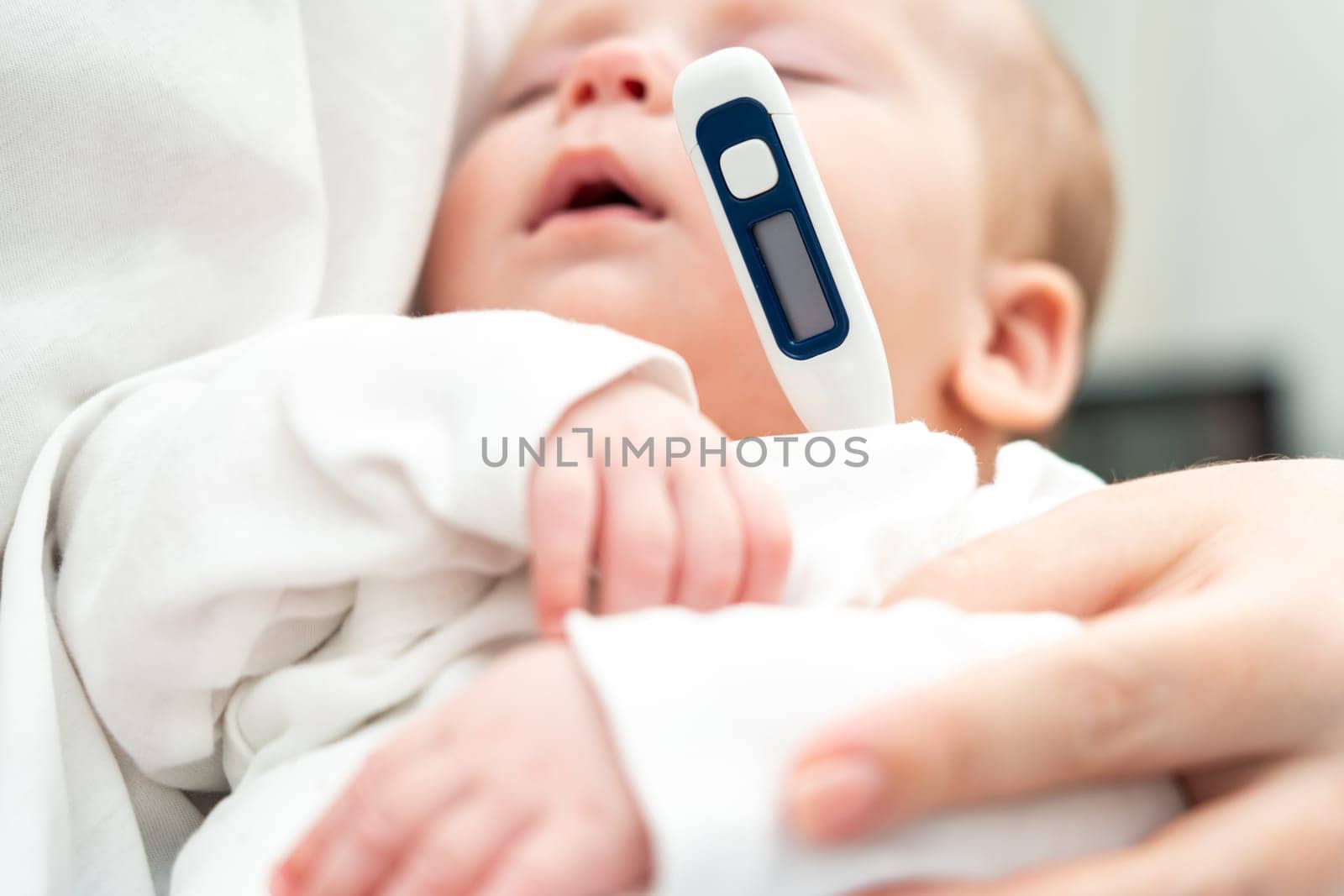 Mother carefully evaluates her baby's condition, utilizing a digital thermometer as the baby sleeps