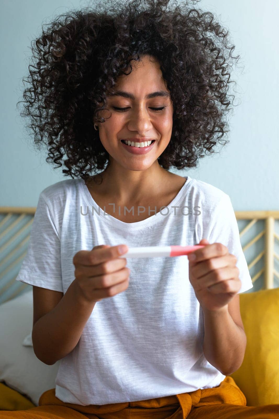 Vertical portrait of happy young multiracial woman checking pregnancy test. Pregnancy.