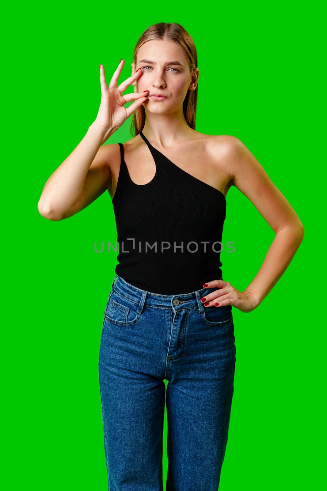 Young Woman Gesturing Silence With Finger on Lips Against Green Screen Background in studio