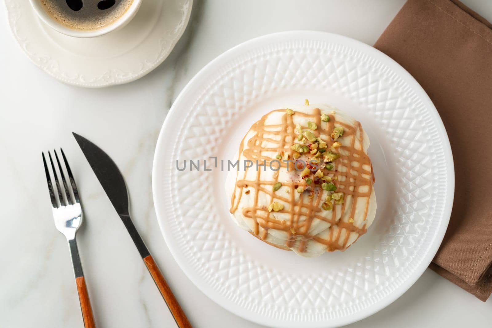 Cinnamon roll bun with icing on plate by Fabrikasimf