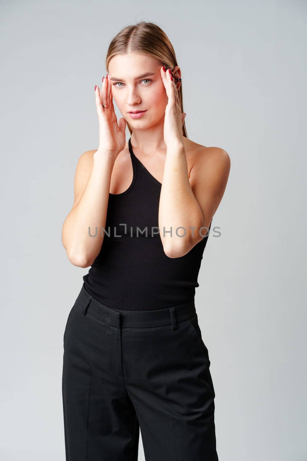 Young Woman Model in Black Top and Pants Posing on gray background by Fabrikasimf