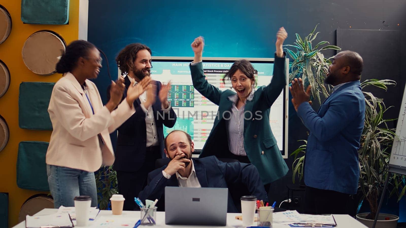 Joyful proud employees celebrating their business success finding out sales results after the launch, executive meeting. Cheerful happy coworkers jumping and enjoying their win. Camera B.