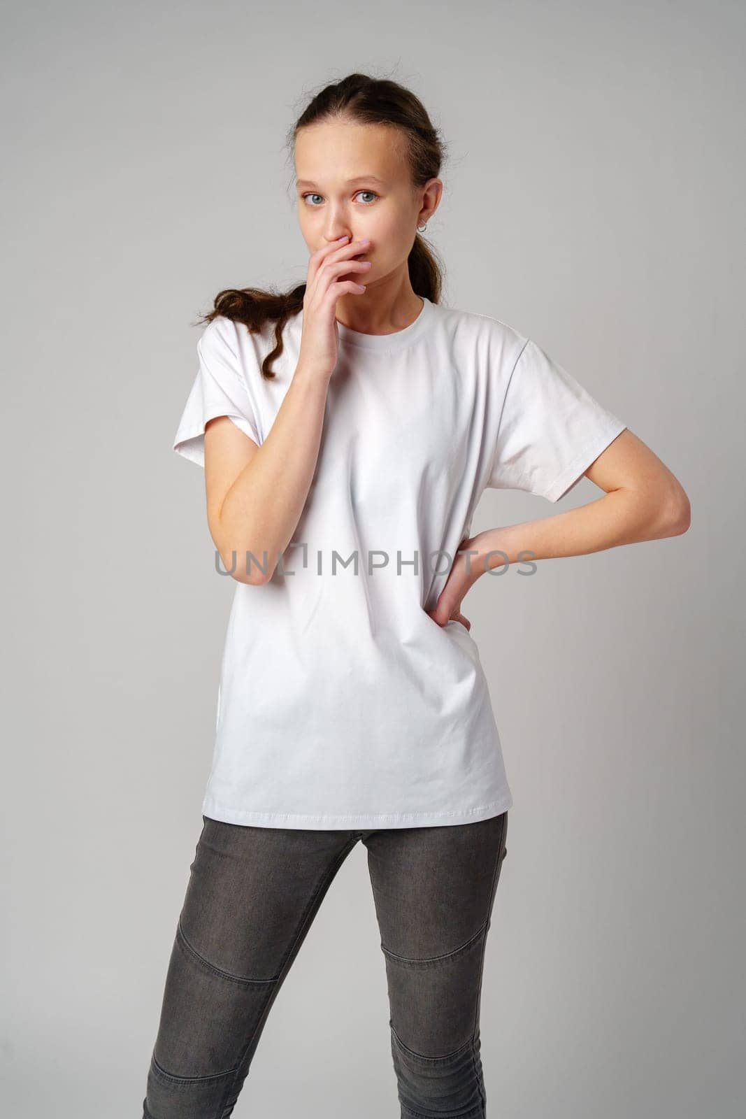 Young Woman Covering Her Face With Her Hands in Fear on gray background by Fabrikasimf