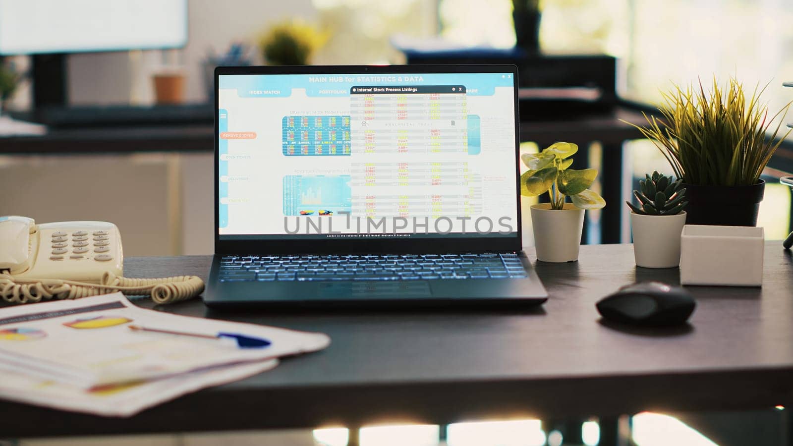 Stock market diagrams with charts and stock figures on laptop sitting on desk in empty workplace. Trading index listings displayed on notebook screen in financial department, panning shot