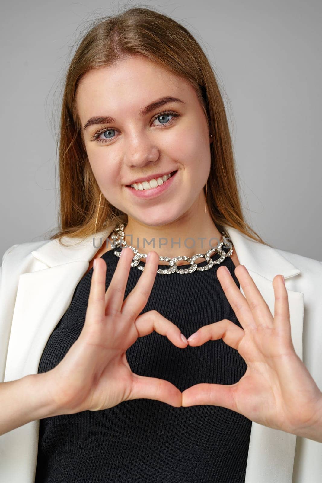 Woman Making Heart With Hands on gray background in studio