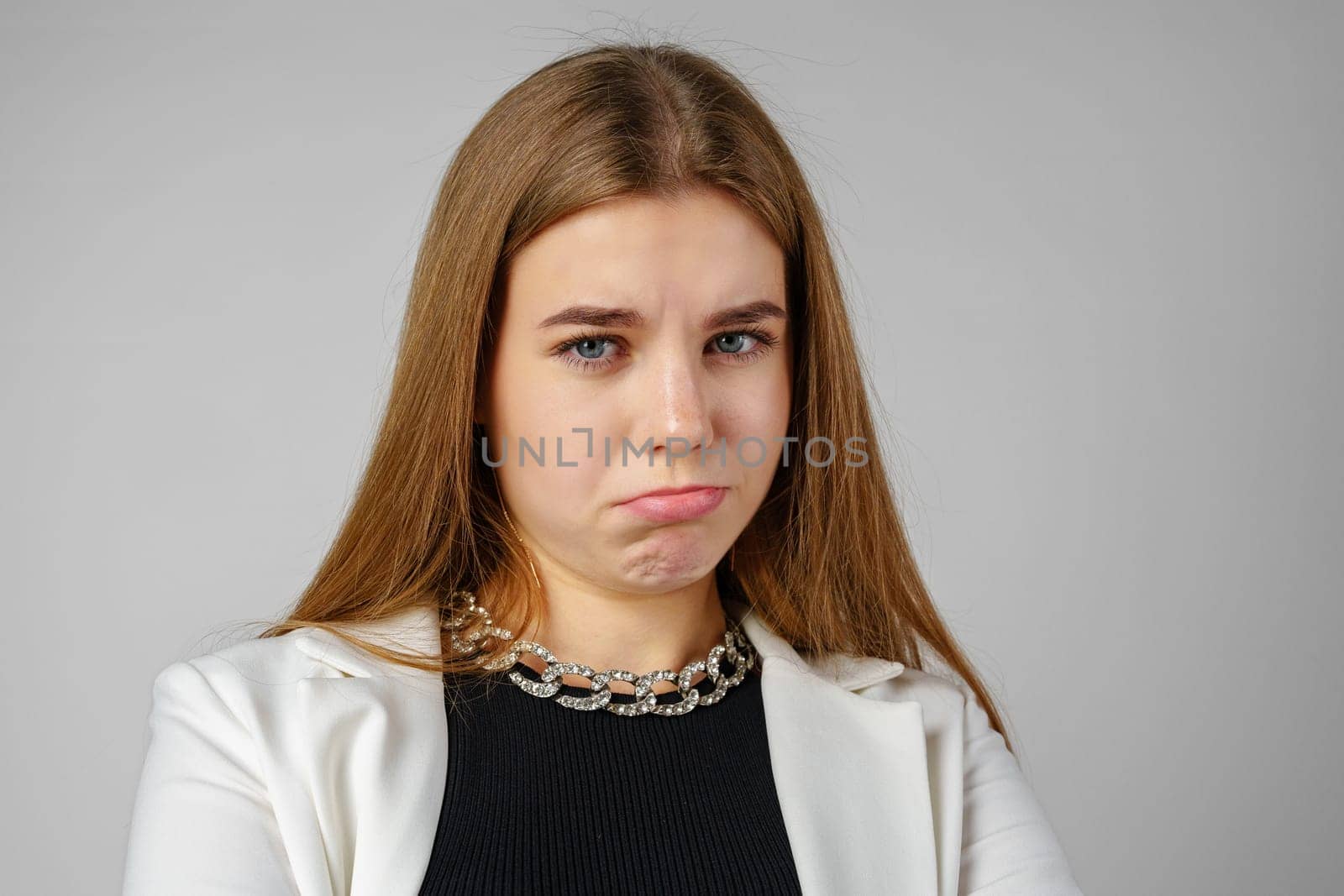 Young Woman Expressing Discontent against gray background in studio