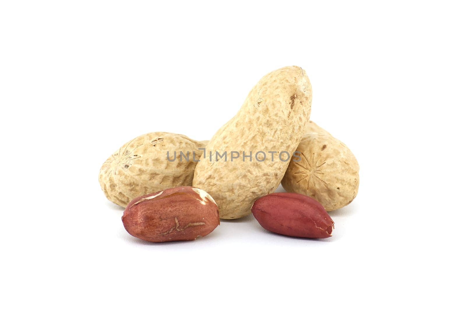 Pile of shelled and unshelled dried peanuts scattered on white background