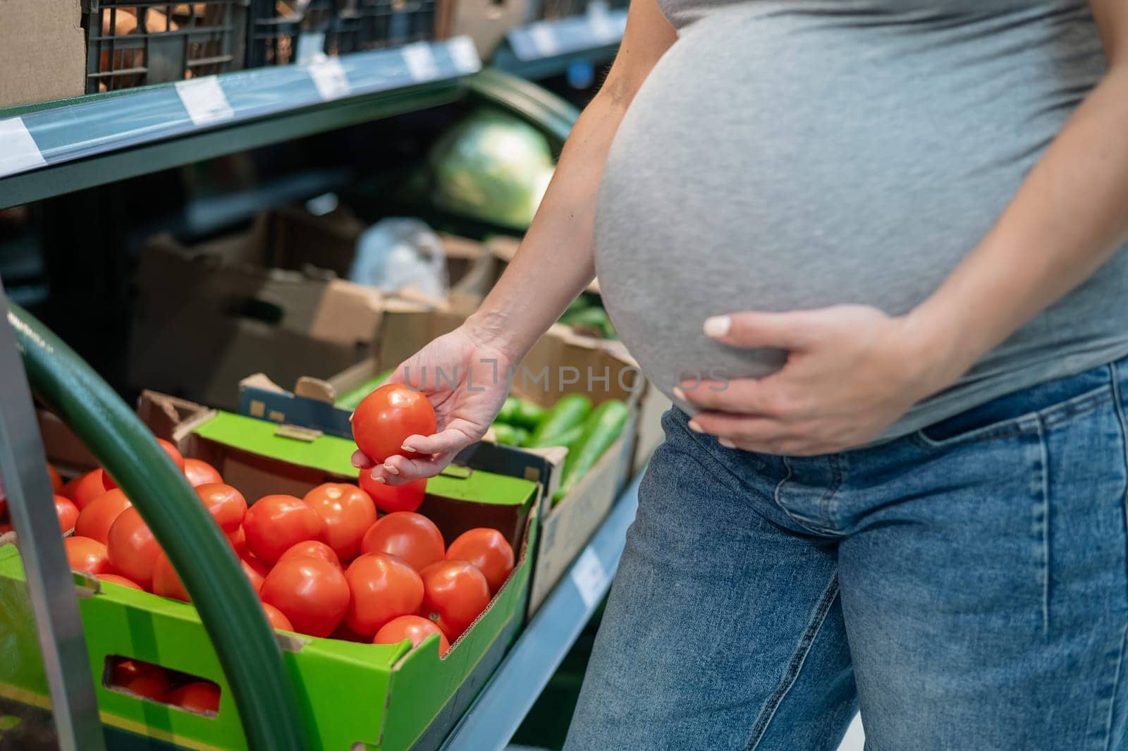 Pregnant woman buys tomatoes in the store. by mrwed54