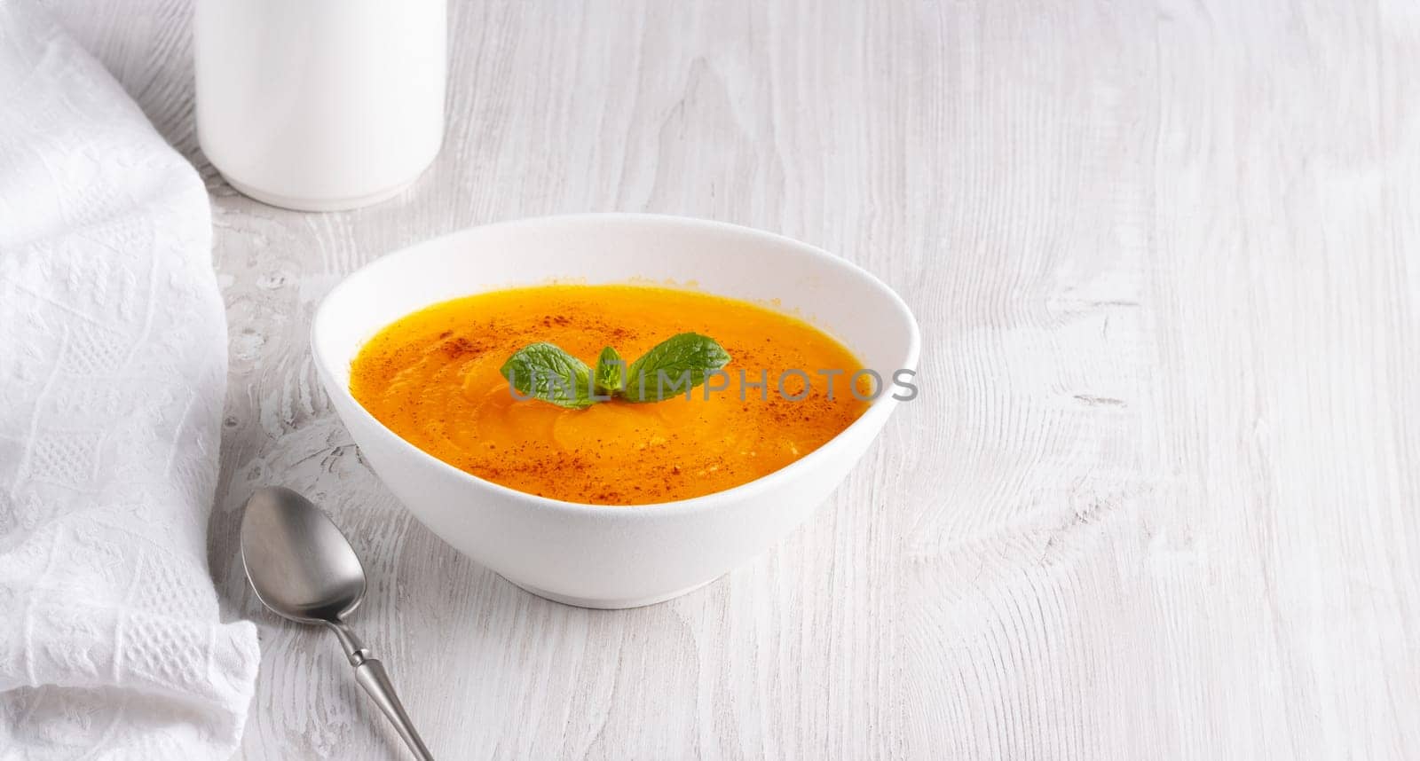 Pumpkin soup on a white wooden table, with copy space for text.