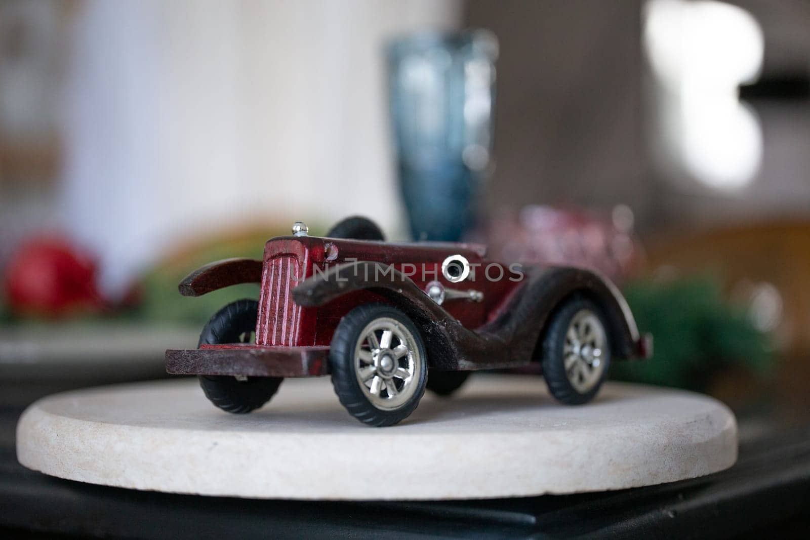 small wooden model of an old retro car, on a white podium