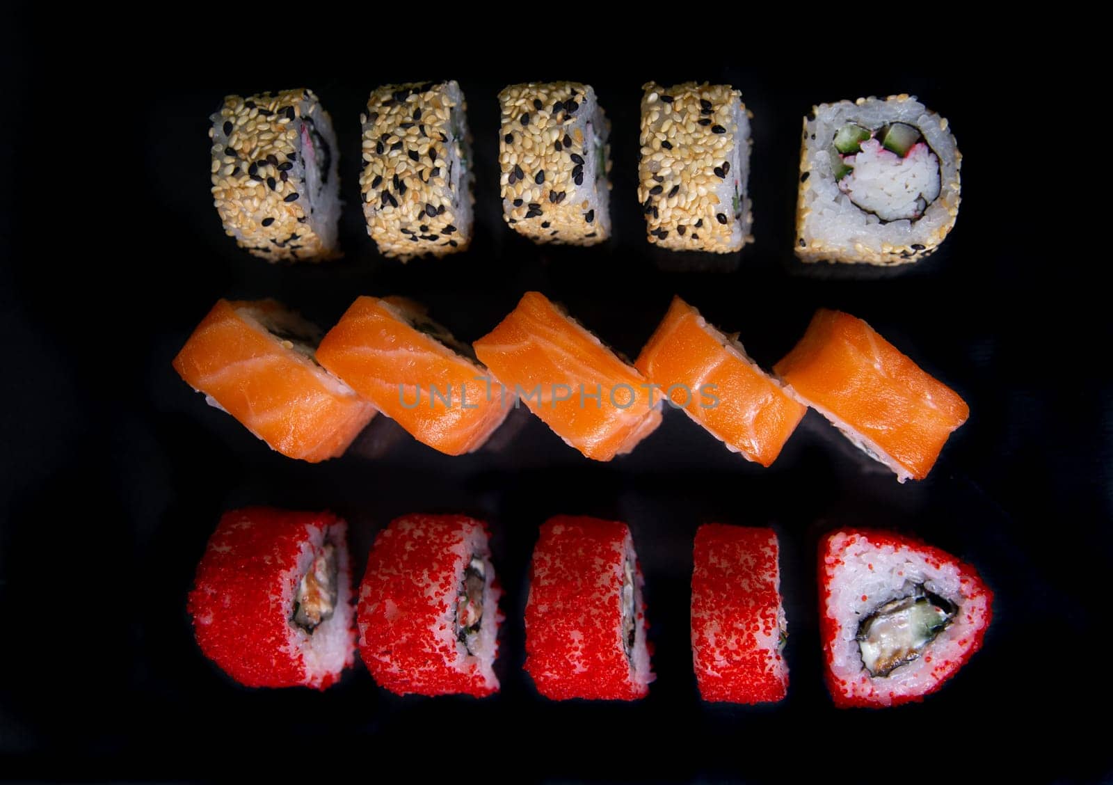 set of Japanese sushi rolls on a black background top view.