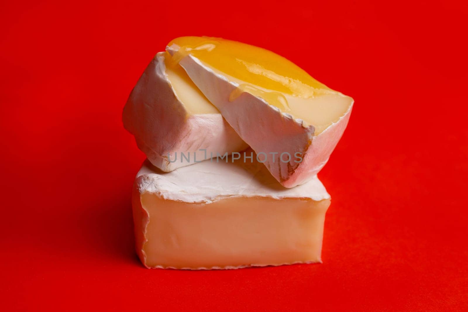 soft cheese with white mold and honey on a red background