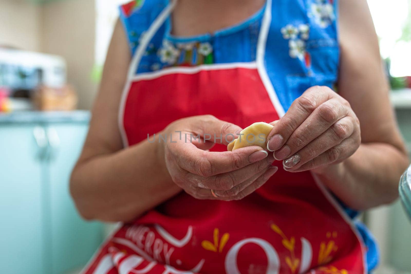 a woman in the kitchen prepares dumplings from dough and minced meat.