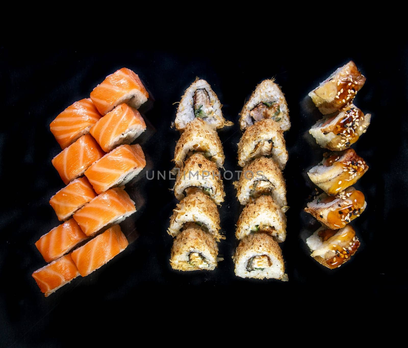 set of Japanese sushi rolls on a black background top view.