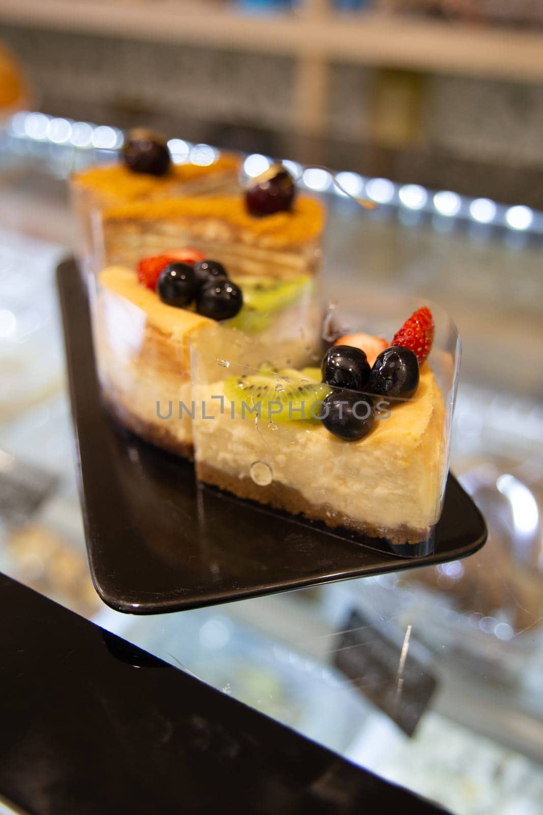 dessert on a cooking showcase. cake with berries on a black plate