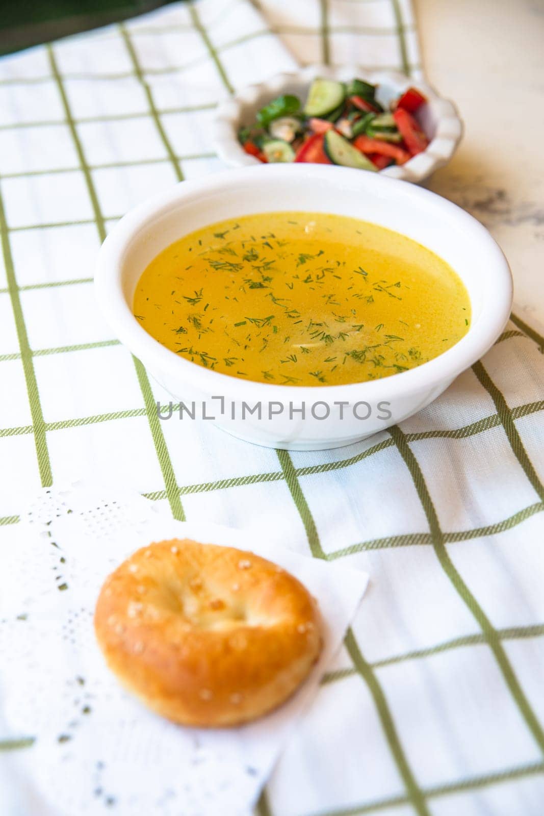 homemade chicken soup with white bread and salad. Lunch on a white tablecloth