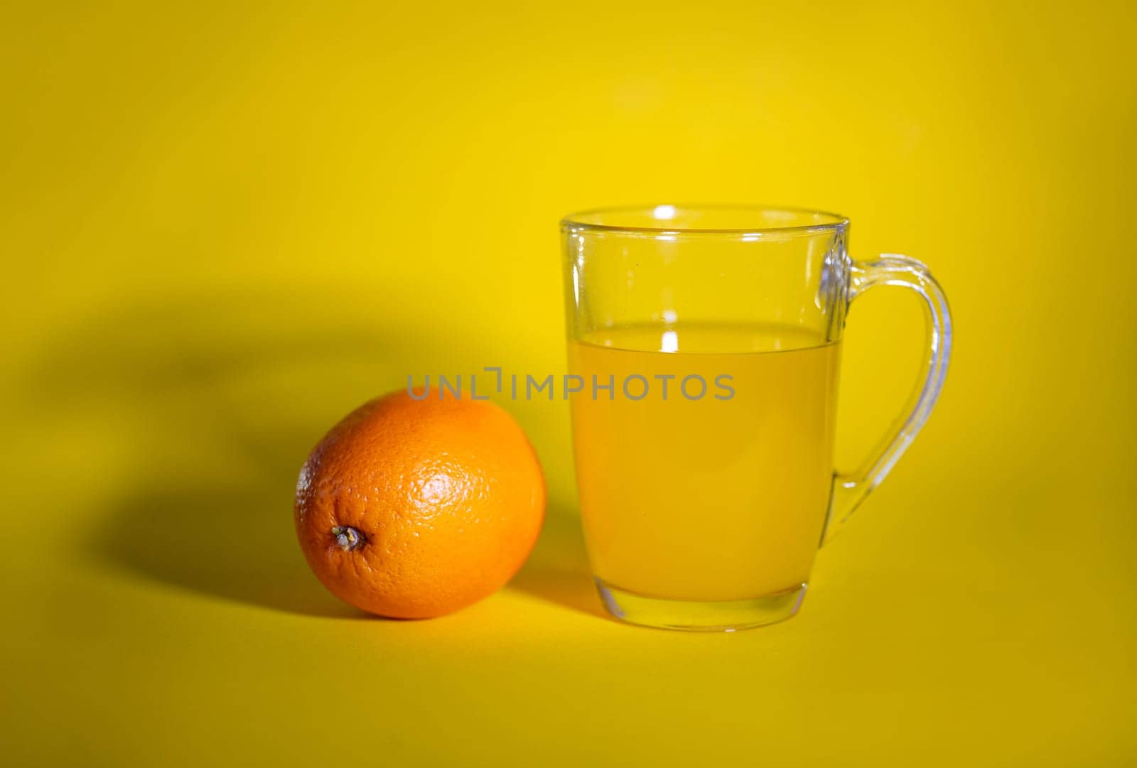 orange and a glass of orange juice on a yellow background