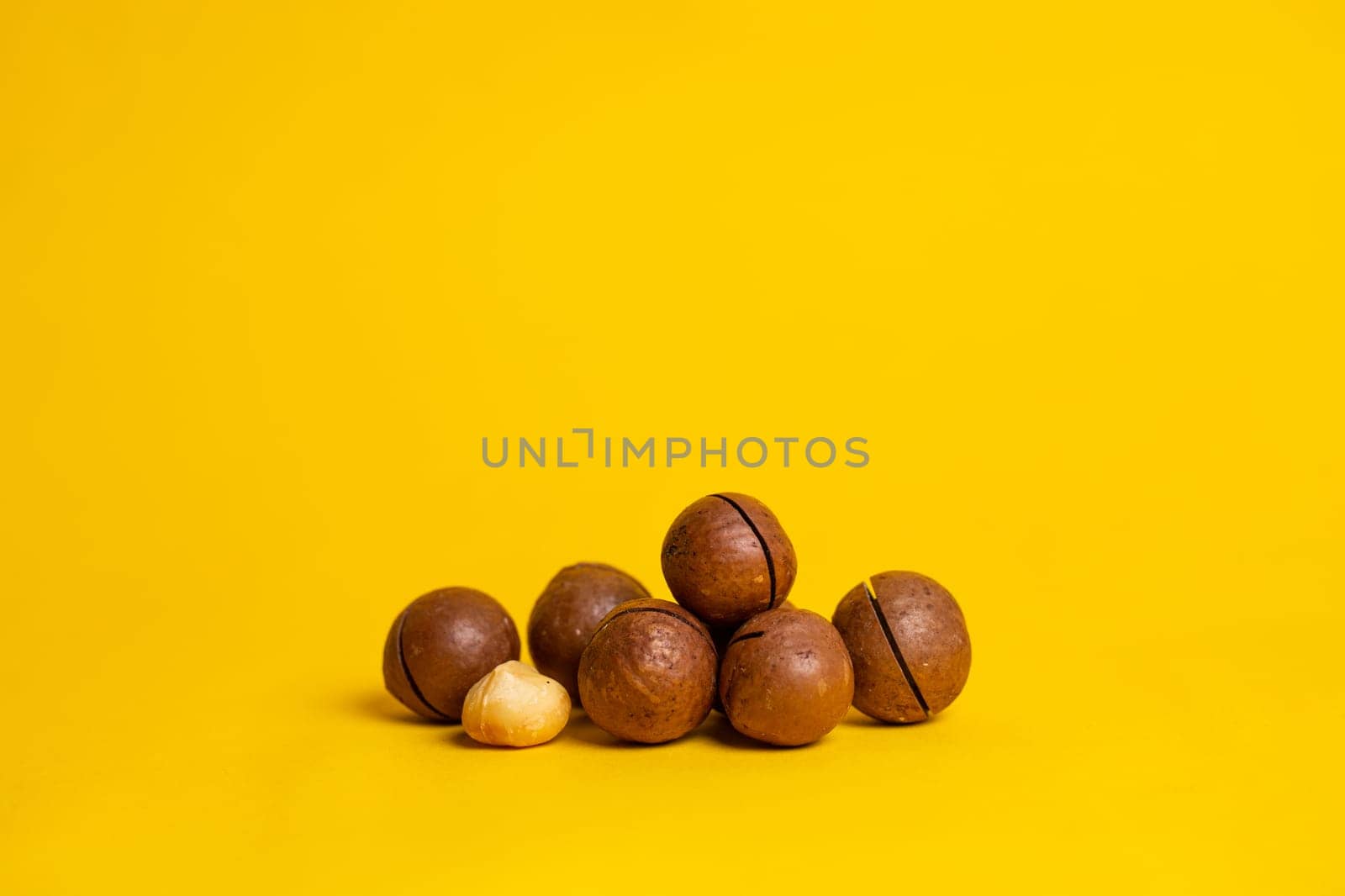 delicious and high-calorie macadamia nut on a yellow background.