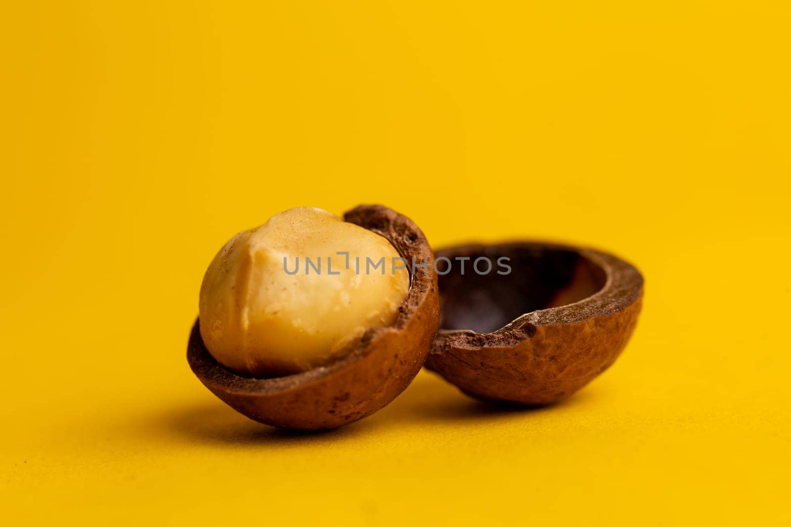 delicious and high-calorie macadamia nut on a yellow background by Pukhovskiy