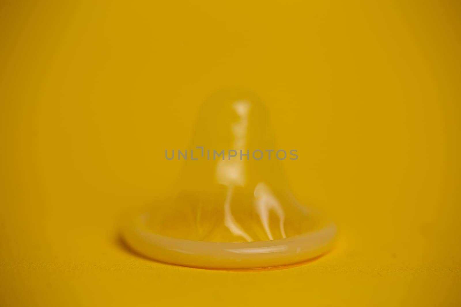 latex condom close-up on a yellow background.