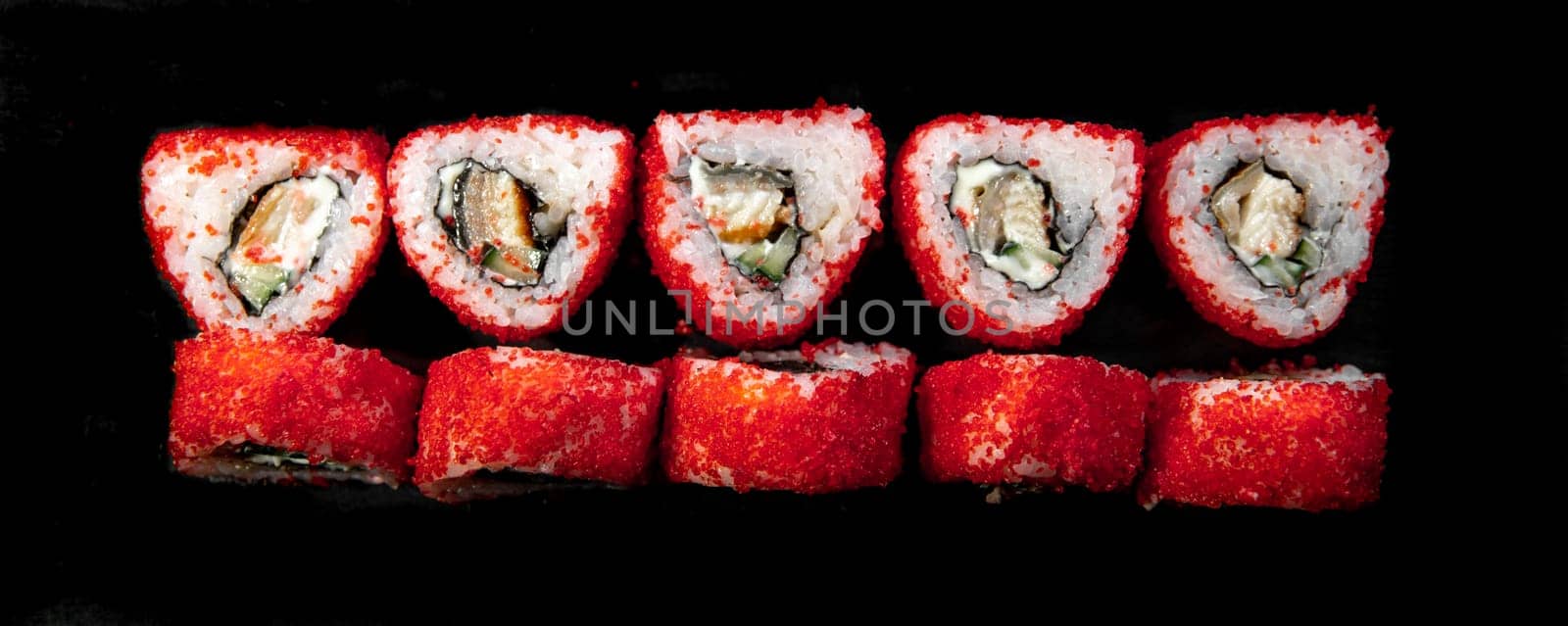 red triangular japanese rolls top view on a black background by Pukhovskiy