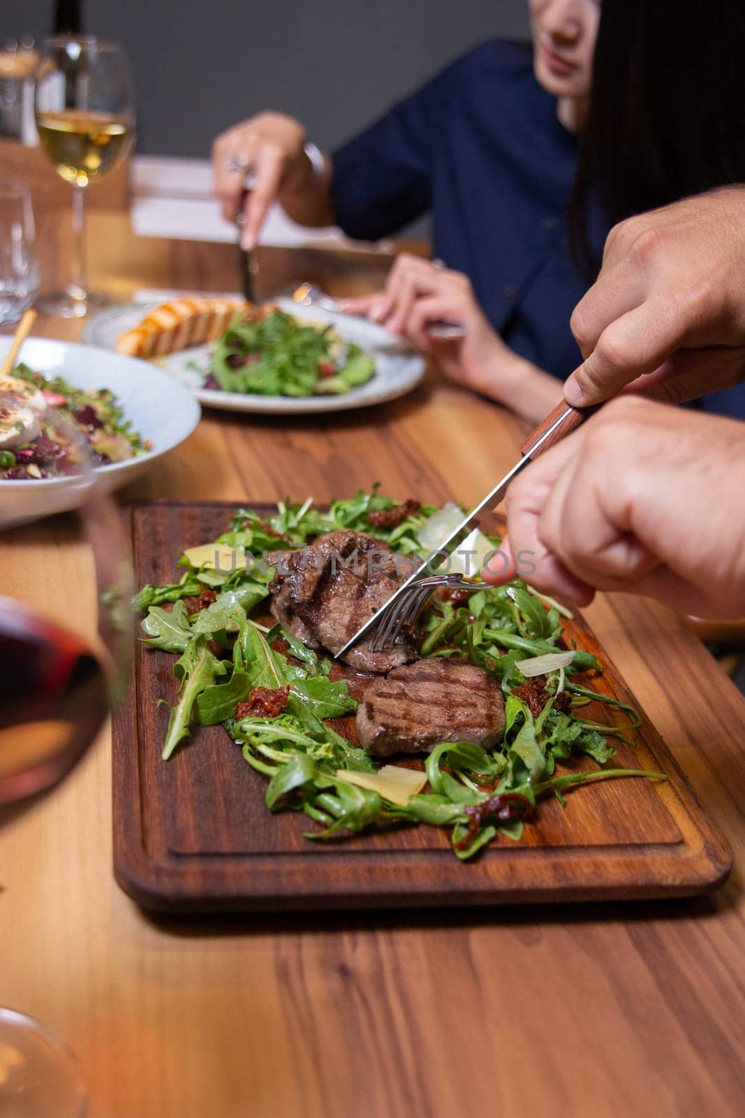 man in the cafe eats beef steak with greens close-up.