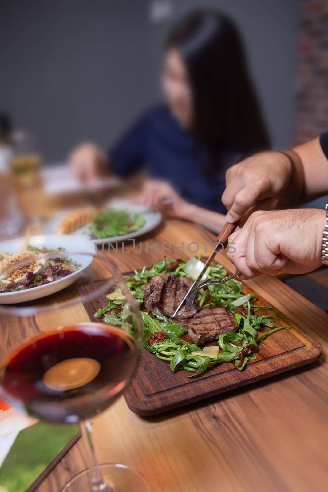 man in the cafe eats beef steak with greens close-up.