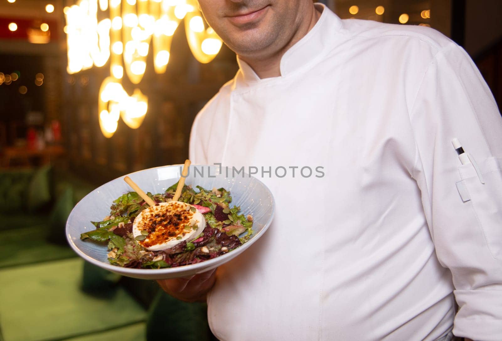 Chef in white shape with dish in hand.