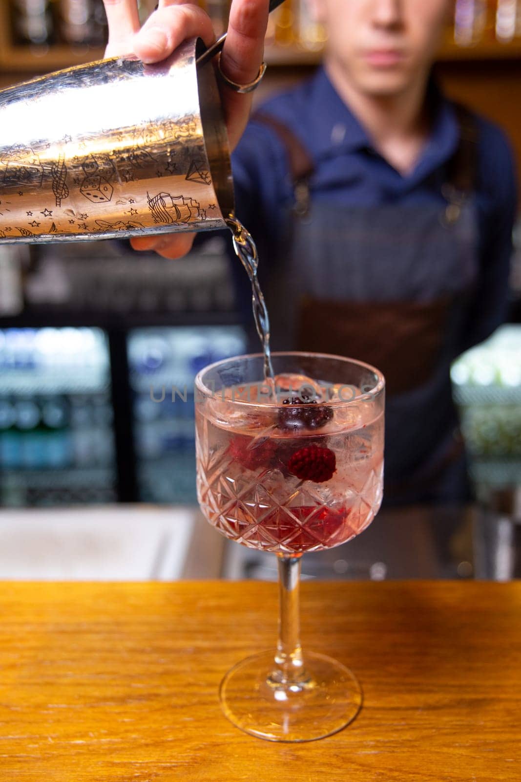 Bartender prepares a cocktail with berries at the bar