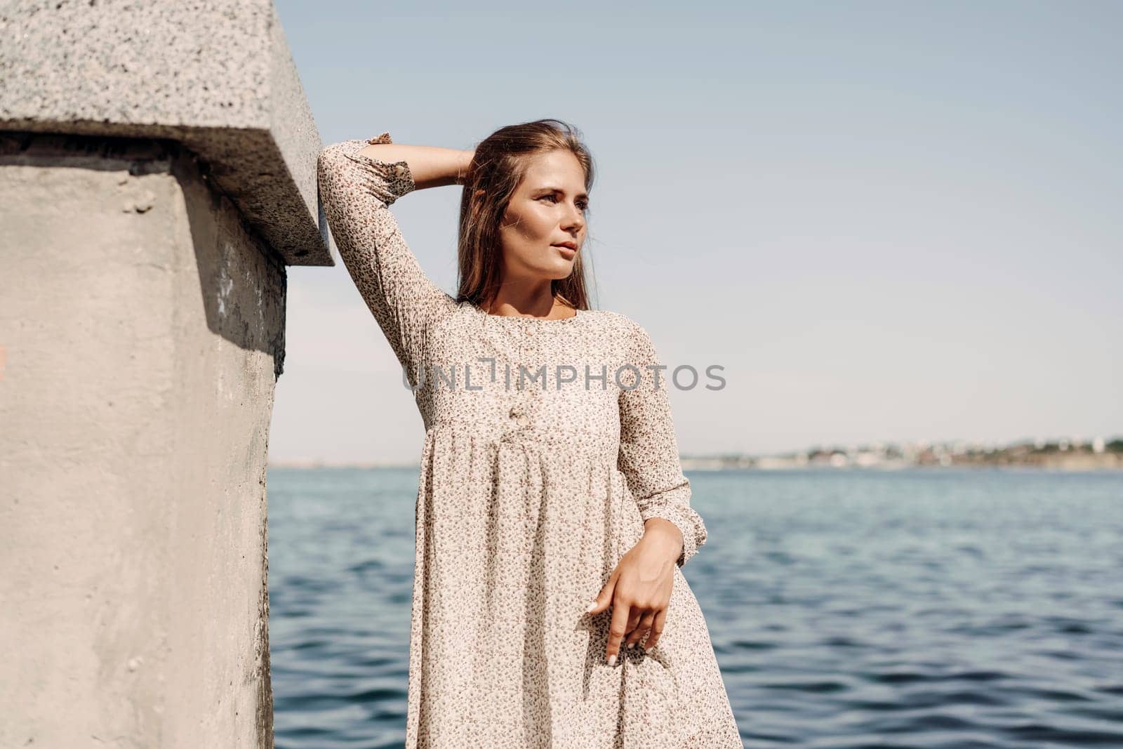 A woman is standing on a dock by the water, wearing a dress and a pair of black shoes. She is smiling and she is happy. by Matiunina