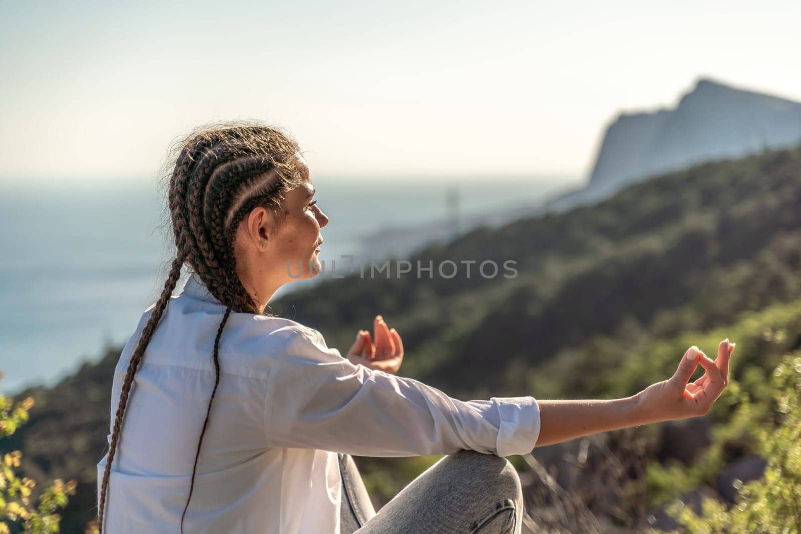 woman doing yoga in the top of a cliff in the mountain. Woman meditates in yoga asana Padmasana by Matiunina