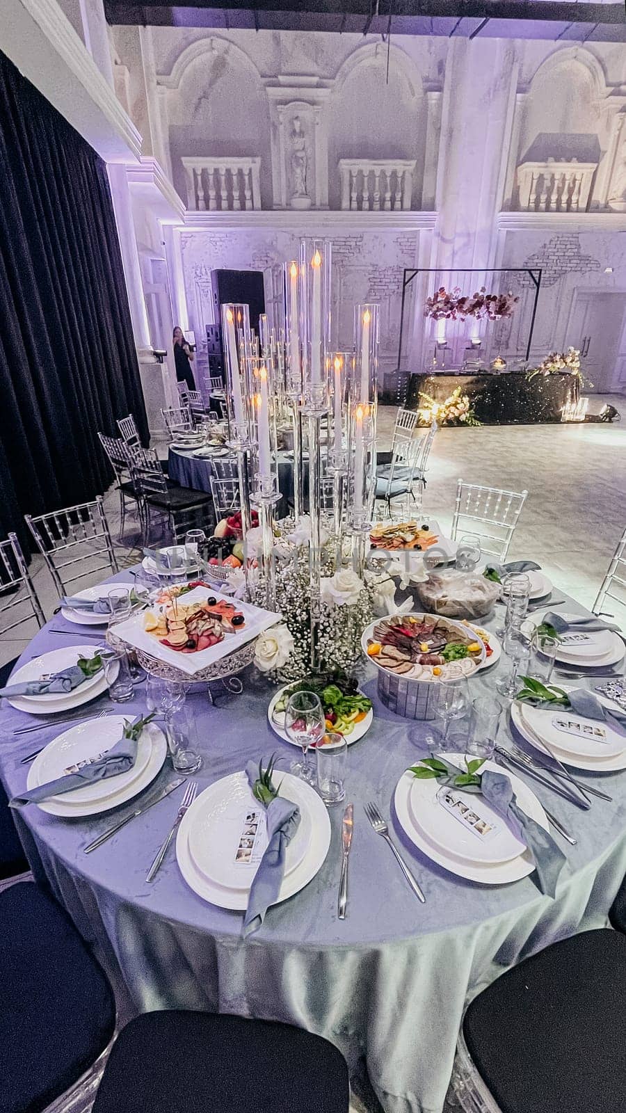 Elegant wedding reception hall with round tables and crystal chandeliers by Pukhovskiy